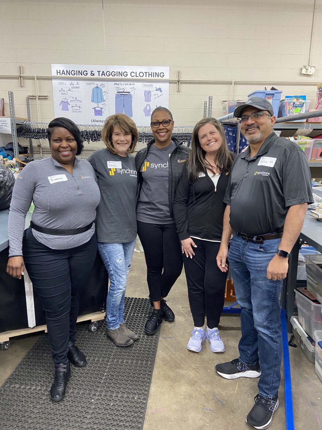 volunteers from synchrony pose in the thrift shop