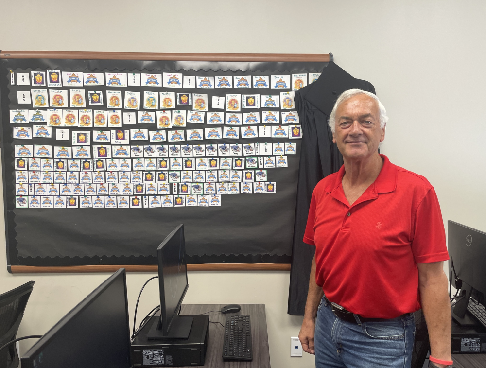 Lee Nichols poses in front of GED bulletin board
